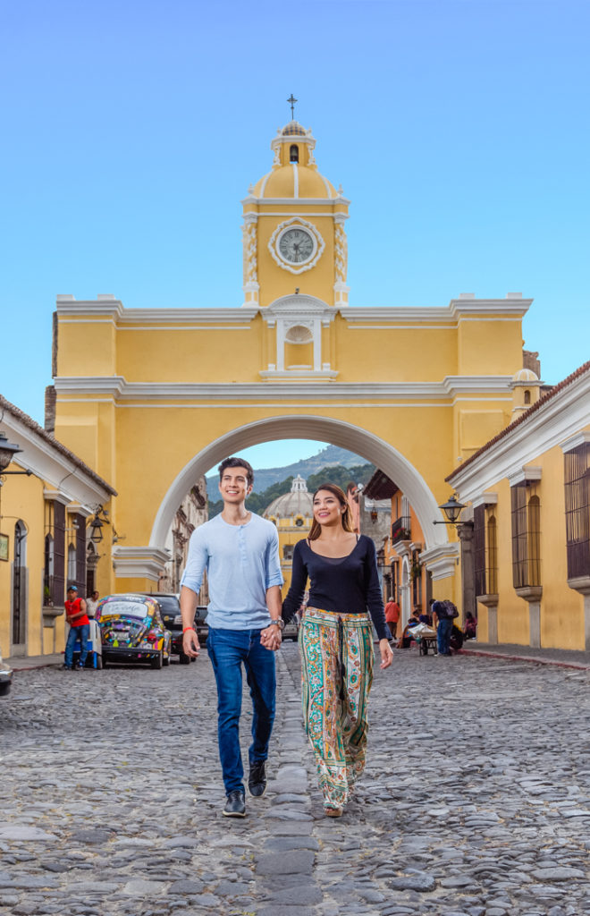 Pareja caminando por el arco de Santa Catalina en Antigua Guatemala