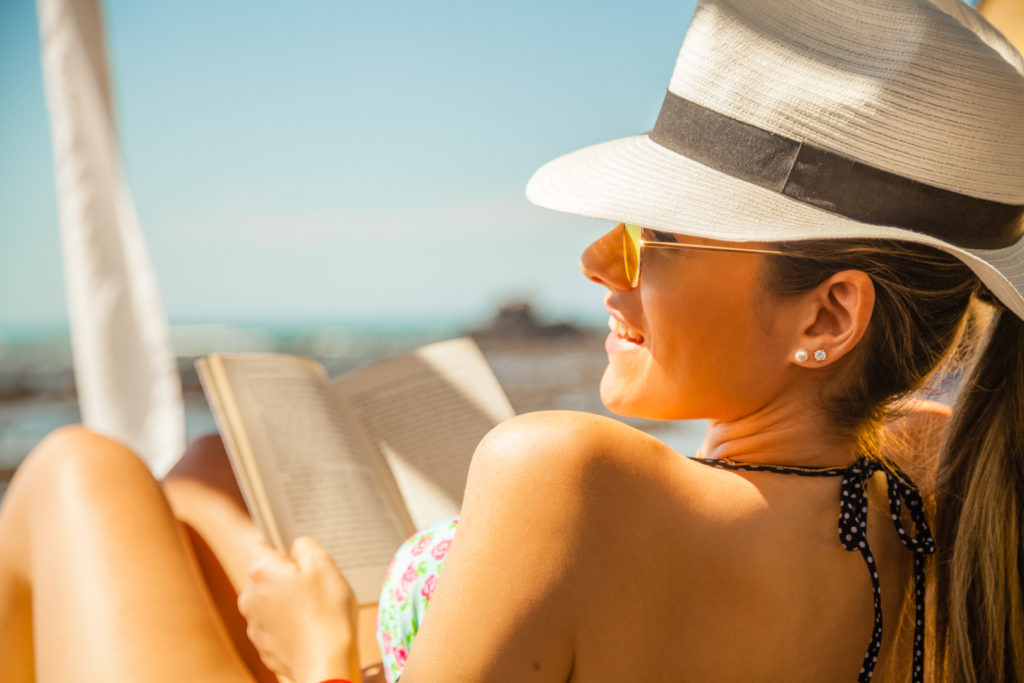 mujer disfruta su lectura en la playa